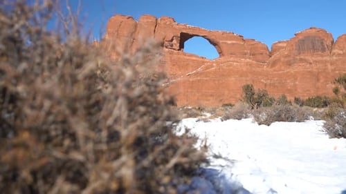 Parc national des Arches, Utah, États-Unis, par une journée ensoleillée d'hiver. Skyline Arch, buissons et neige par beau temps