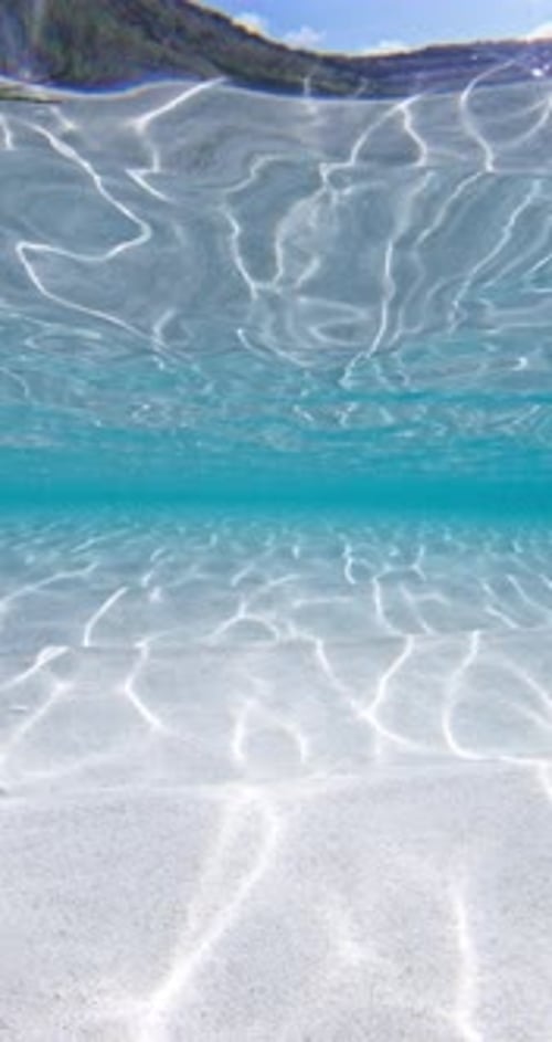 Océano azul tropical con arena blanca, fondo de agua vertical bajo el agua