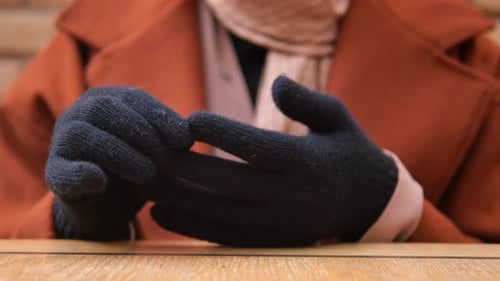 Person Removes Black Wool Gloves on Table
