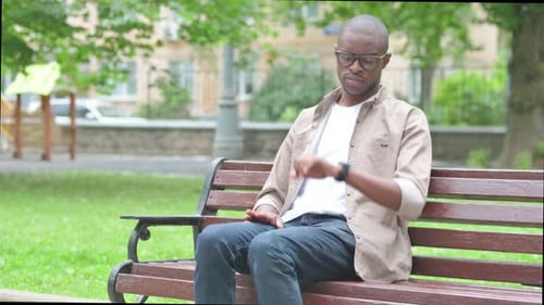 Waiting Young African Man Checking Wrist Watch on Park Bench