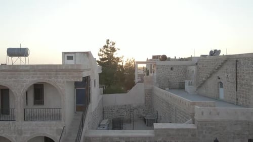 Rising drone reveal of dense stone city at sunset with distant minaret in Mardin Turkey