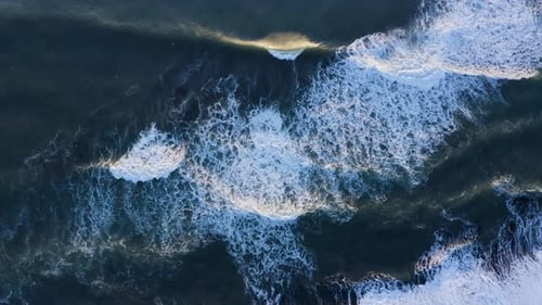 Waves Breaking On The Black Sandy Shore Of A Quiet Secluded South Coast Beach - aerial drone