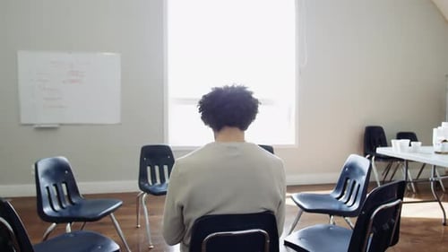 Young man seated in community center reads waiting for support group