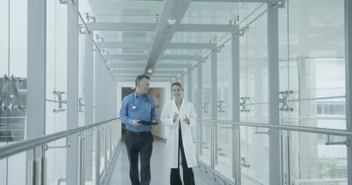 Doctors walking through hospital corridor discussing results on a digital tablet