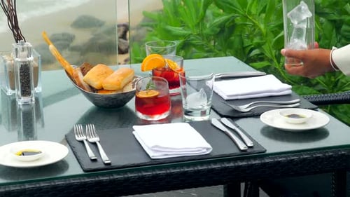 At a Table Overlooking the Sea a Waiter Caters to Guests at a Restaurant