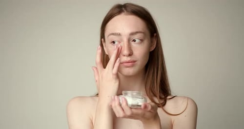 Woman Applies Cream for a Facial Beauty Treatment