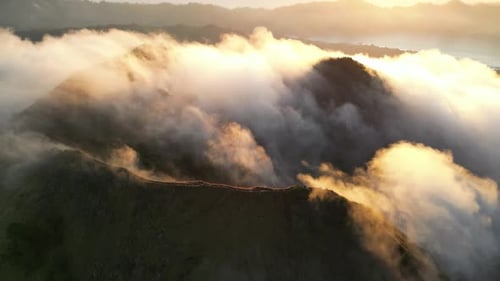 Aerial shot of Batur volcano crater in clouds at sunrise, Bali, Indonesia