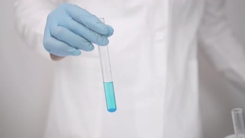 Gloved Hand Holding Test Tube With Blue Liquid