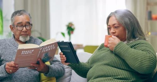Senior Couple Reading Book and Tablet on Couch