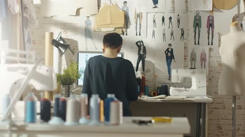 Back view of a Female fashion, designer, Working on a Personal Computer, Taking Notes. Her Workpla