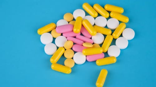 Pile of Multicolored Pills on Blue Background