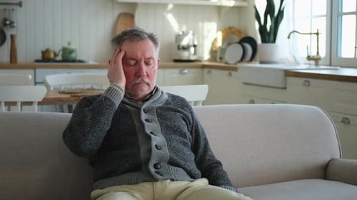Man Sitting on Couch with Headache