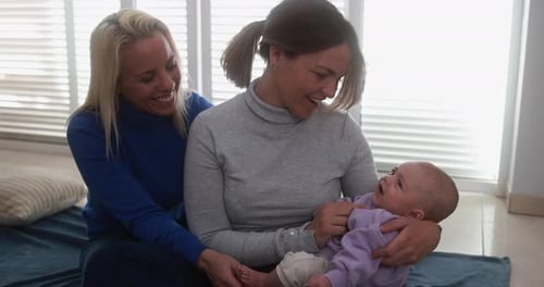 Female Gay Couple Having Tender Moment with Their Baby Son at Home