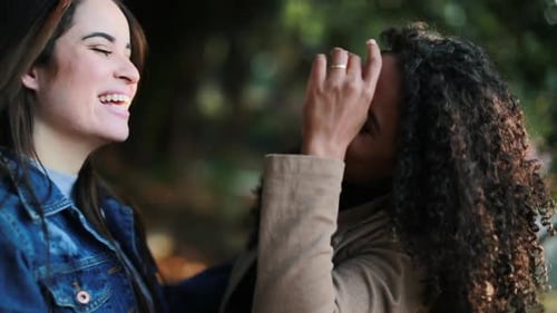 Happy two diverse girlfriends reunion. Friends embrace and hug outside at park