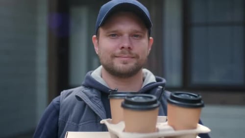 Porträt eines jungen Kurierzustellers, der Pizza in Kartons hält und auf einen Kunden wartet