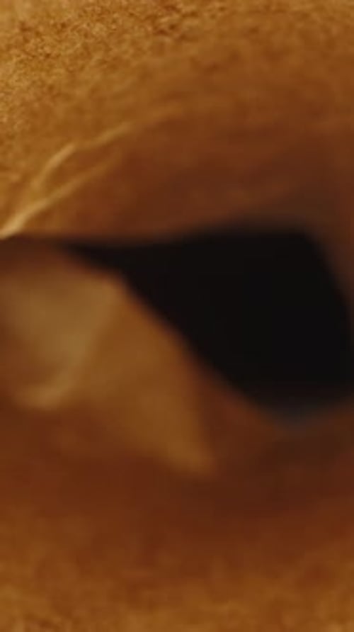 Vertical video. Brown baking paper rolled into a tube. Dolly slider extreme close-up.