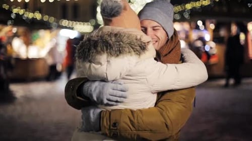 Couple Embraces at Christmas Market at Night