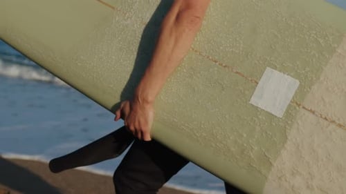 Surfer Man Walking to the Beach at Sunset Preparing for Surfing Training and Search for Waves in