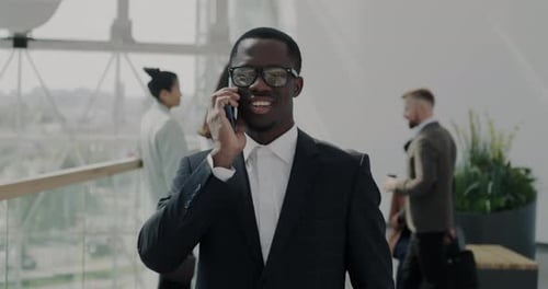 Slow Motion Dolly Shot of Businessman in Suit Walking in Office Lobby and Talking on Mobile Phone