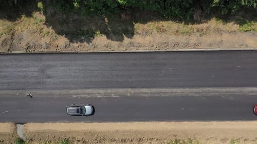 Top view of cars moving on new asphalt road. View from above on finished part of the road.