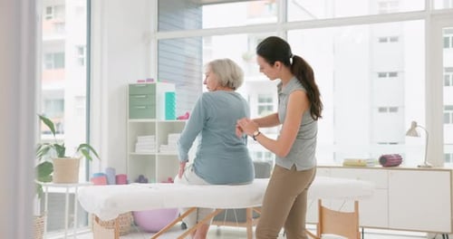 Woman Examines Senior Woman's Back in Clinic