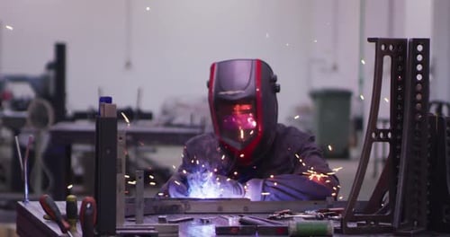 Kleinunternehmen, Industriearbeiter in der Werkshalle, die Stahl in Zeitlupe schweißen