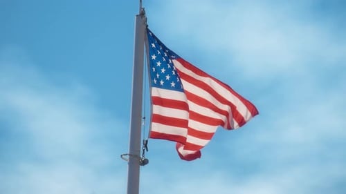 American Flag Waving Against Blue Sky Background