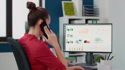 Woman Working at Computer, Talking on Phone in Office