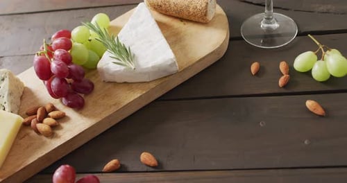 Vidéo de fromages, de pain, de raisins et de noix à bord et d'un verre à vin sur une table en bois, avec espace de copie
