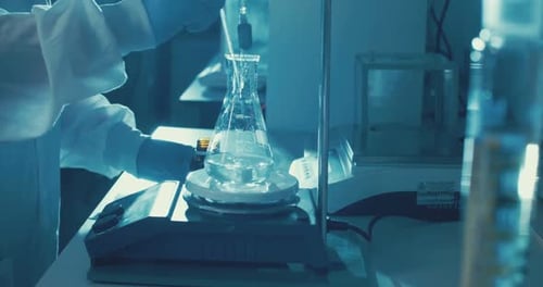 Lab Scientist Adding Liquid to Beaker in Lab