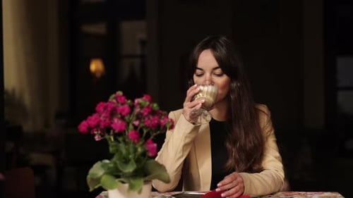 Woman Enjoys Latte at Cafe Table at Night