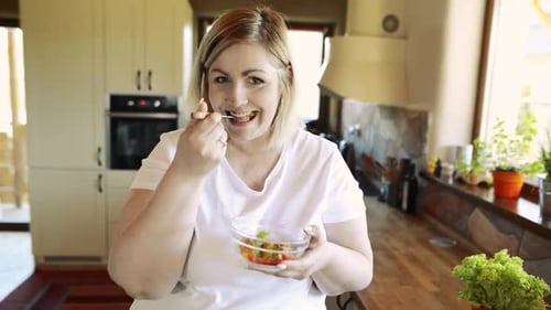 Woman Eats Salad in Bright Kitchen