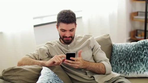 Man relaxing on sofa using his smartphone