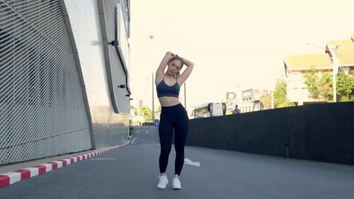 Young Woman Stretching on an Empty Urban Street
