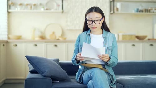 Woman Reading Happy News on Sofa at Home