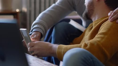 Affectionate gay couple bonding over social media in their apartment living room