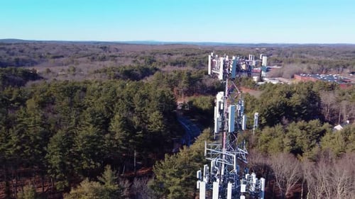 4K aerial drone orbit around a cellular phone tower in wooded suburb