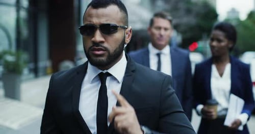 Serious, employee and bodyguard in the city, walking and protection with sunglasses