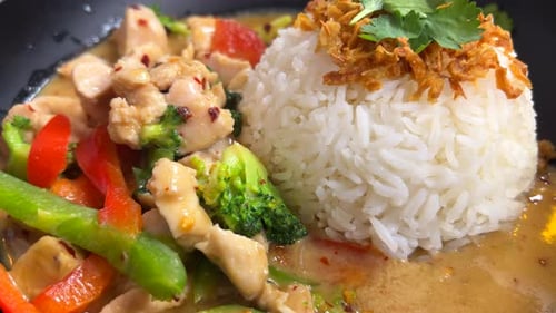 Traditional Thai green curry chicken dish with vegetables, crispy fried onion and rice, Thai cuisine