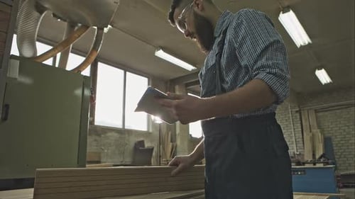 Carpenter Using Tablet in Sunny Workshop