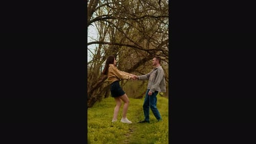 A young couple holding hands run through the forest, embodying an active lifestyle and tourism. Spor
