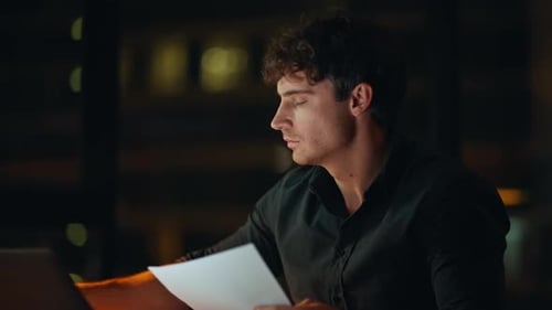 Tensed Freelancer Reading Documents at Dark Workplace Closeup Worried Man