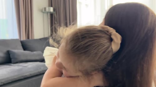 Little Girl Emotionally Hugging Her Mother in Home Living Room