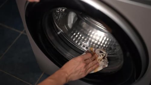 Hands Cleaning Inside of Washing Machine with Towel