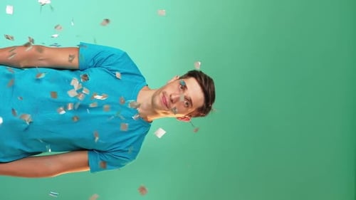 Young Man Celebrates with Confetti Against Green Screen
