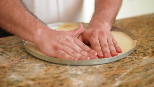 Hand Adjusting Fresh Pizza Dough in Pan