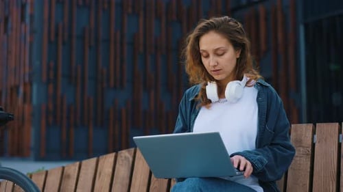 Caucasian Smiled Woman Freelancer Sitting on the Bench Working on the Laptop Near the Office Centre