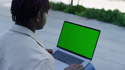 Man Using Laptop with Green Screen Outdoors