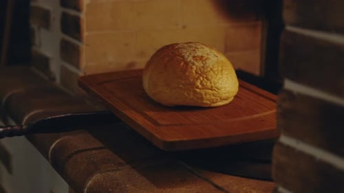 Traditional bakery worker chef placing bread on a tray in a traditional stone oven