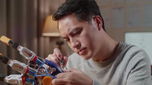Close Up Of Asian Male Repairing A Cyborg Hand At Home